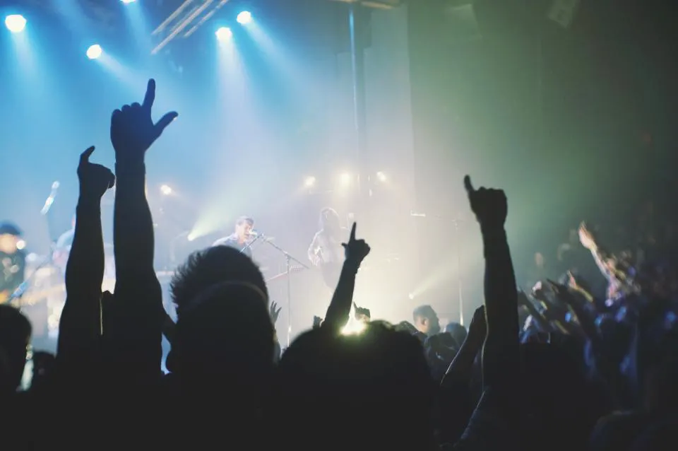 The crowd with hands up under blue stage light