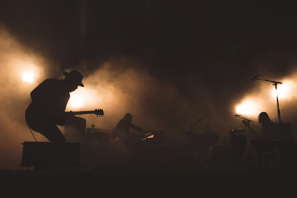 The band in silhouette on a smoky stage, a guitarist stepping up onto the monitor