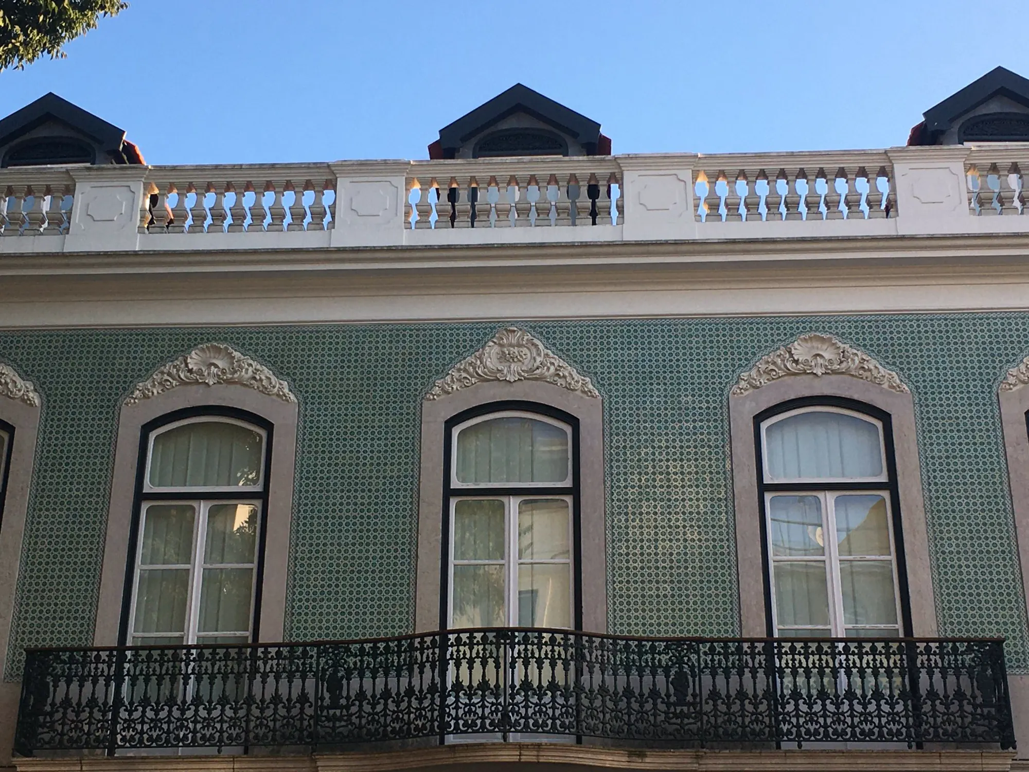 The front of a tiled townhouse with wrought-iron balconies and tall windows