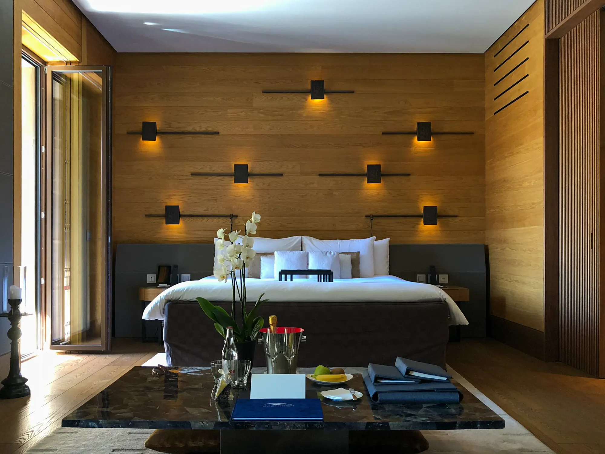 A wood-panelled bedroom with reading lamps set into the wall above a wide bed