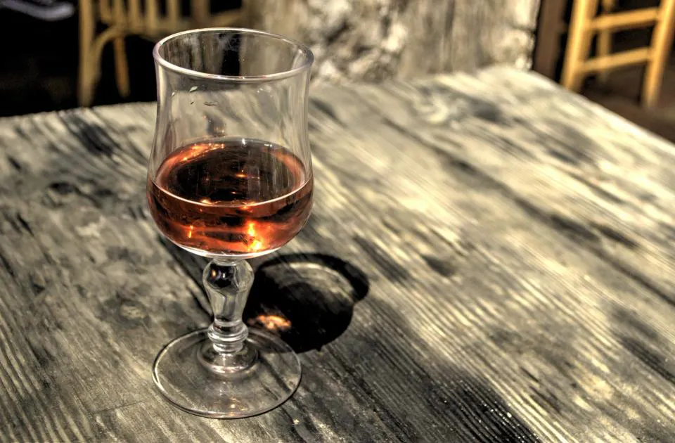 A glass of tawny port on a worn wooden table