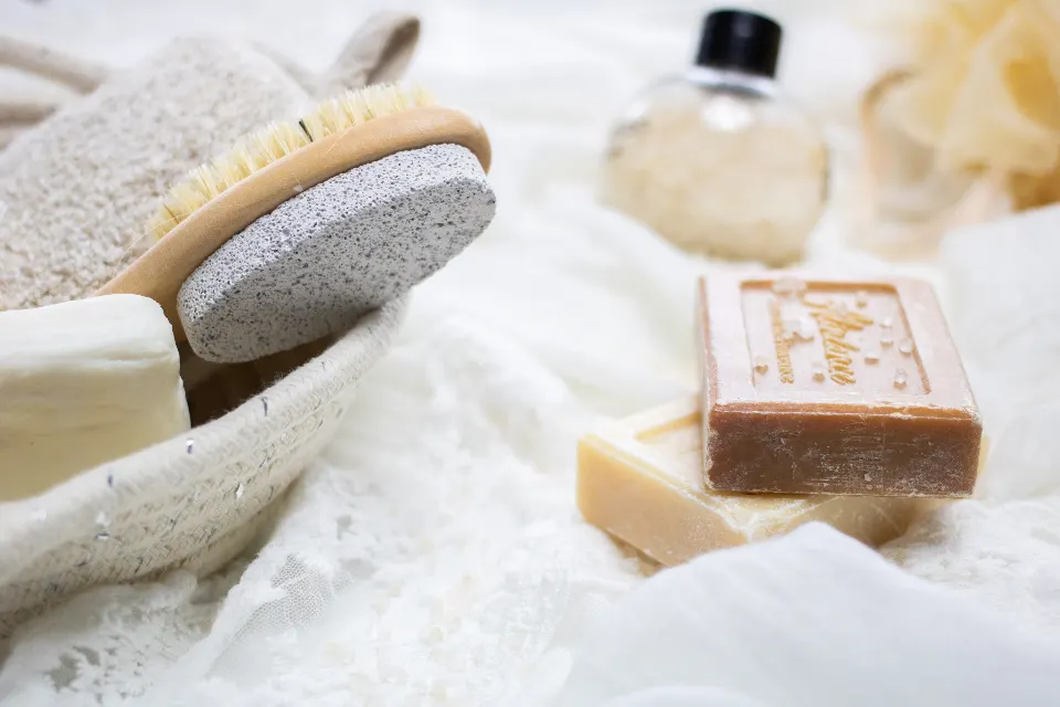 Bars of plain soap, a pumice stone and a wooden brush on a white cloth
