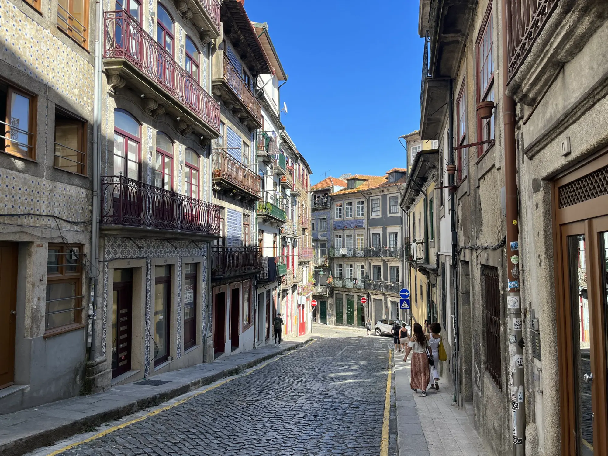 A cobbled street in Porto between tall houses with iron balconies